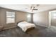 Spacious bedroom featuring carpet, a ceiling fan, and plentiful natural light from two windows at 16562 W Sierra St, Surprise, AZ 85388