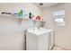 Bright laundry room features a window, shelving, and modern washer and dryer at 16562 W Sierra St, Surprise, AZ 85388