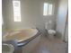 Bathroom with a soaking tub, a toilet, and two windows at 2028 E Libby St, Phoenix, AZ 85022
