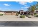 Inviting single-story home with lush landscaping, mature palm trees, and a spacious three-car garage at 20609 N Canyon Whisper Dr, Surprise, AZ 85387