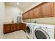 Spacious laundry room featuring wood cabinets, counter space, and modern washer and dryer at 20609 N Canyon Whisper Dr, Surprise, AZ 85387