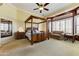 Bright main bedroom featuring a four-poster bed, sitting area, and expansive windows at 20609 N Canyon Whisper Dr, Surprise, AZ 85387