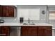 Close-up of kitchen sink, counter tops, and stainless steel appliances with dark wood cabinets and a window above at 2136 W Pickett Ct, San Tan Valley, AZ 85144