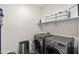 Bright laundry room featuring gray front-load machines, white shelving, and modern storage bins at 31020 N 5Th St, Phoenix, AZ 85085