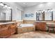 Bright bathroom showcasing a soaking tub, dual vanities, decorative tile, and wood cabinetry at 32020 N 20Th Dr, Phoenix, AZ 85085