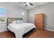 Bright bedroom with wood floors, ceiling fan, a queen bed, and a wood dresser at 32020 N 20Th Dr, Phoenix, AZ 85085