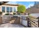Outdoor kitchen featuring a grill, sink, and storage space, with stone steps leading to the upper patio area at 32020 N 20Th Dr, Phoenix, AZ 85085