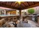 Outdoor kitchen boasts a built-in grill, bar seating, and a cozy fireplace overlooking the pool and patio area at 32020 N 20Th Dr, Phoenix, AZ 85085