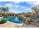 Backyard oasis with rock waterfall cascading into a turquoise pool and spa under a sunny blue sky at 32020 N 20Th Dr, Phoenix, AZ 85085