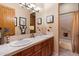 Bathroom featuring dual sinks, wooden cabinets, framed mirrors and a shower/tub combo at 33269 N 73Rd Pl, Scottsdale, AZ 85266