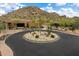Community entrance with meticulously landscaped circular island, desert plants, and a backdrop of mountains at 33269 N 73Rd Pl, Scottsdale, AZ 85266