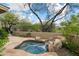 Close up of backyard water feature with rock waterfall, lush landscaping, and mature trees at 33269 N 73Rd Pl, Scottsdale, AZ 85266