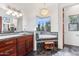 Bright bathroom with cherry cabinets, a corner bathtub, a window view, and stone countertops at 38199 N Tranquil Way, Carefree, AZ 85377