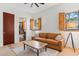 Bright living room featuring wood floors, shutters on windows, and tan sofa with bathroom view at 38199 N Tranquil Way, Carefree, AZ 85377