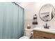 Well-lit bathroom featuring a shower with a blue curtain, modern vanity, and round mirror at 4076 E Silverbell Rd, San Tan Valley, AZ 85143