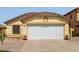 A tan home featuring a two car garage door, desert landscaping, and a tiled roof at 45068 W Alamendras St, Maricopa, AZ 85139