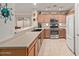 Well-lit kitchen featuring wooden cabinets, stainless steel appliances, tile floors, and a breakfast bar at 45068 W Alamendras St, Maricopa, AZ 85139
