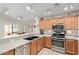 Charming kitchen with stainless steel appliances, wooden cabinetry, and adjacent dining area at 45068 W Alamendras St, Maricopa, AZ 85139