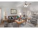 Cozy living room with a leather sofa, ceiling fan, and a decorative mirror at 45068 W Alamendras St, Maricopa, AZ 85139