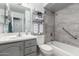 Updated bathroom showcasing a gray vanity, toilet, shower-tub with grab bars, and a shelf with towels at 5221 W Garden Dr, Glendale, AZ 85304