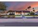 Charming home featuring manicured front yard, lush landscaping, and a welcoming entryway, all complemented by a colorful sunset backdrop at 5975 E Larkspur Dr, Scottsdale, AZ 85254