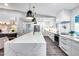 Modern kitchen with white cabinets, waterfall island, stainless appliances, and designer lighting at 5975 E Larkspur Dr, Scottsdale, AZ 85254