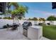 This outdoor kitchen offers seating, modern grill with stainless steel, lush green grass, and backyard views at 5975 E Larkspur Dr, Scottsdale, AZ 85254