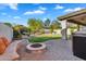 Outdoor seating area and fire pit, with a green lawn and a lovely pool area in the background at 7354 E Norwood St, Mesa, AZ 85207