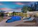 Beautiful backyard features a lagoon style pool with waterfalls and lounge chairs at dusk at 7354 E Norwood St, Mesa, AZ 85207