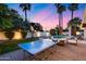 Inviting backyard featuring a ping pong table, pool, lounge chairs, and lush greenery under a colorful sunset sky at 7820 N 5Th Ave, Phoenix, AZ 85021