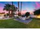 Cozy backyard featuring a modern firepit, comfortable seating, lush landscaping, and swaying palm trees under a colorful sky at 7820 N 5Th Ave, Phoenix, AZ 85021
