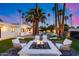 Inviting backyard with a modern firepit, comfortable seating, swaying palms trees and lush landscaping at 7820 N 5Th Ave, Phoenix, AZ 85021