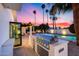 Stylish outdoor kitchen featuring a built-in grill, counter space and serene views of the pool and palm trees at 7820 N 5Th Ave, Phoenix, AZ 85021