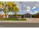 Lovely home featuring a well-kept lawn, mature tree, and a driveway leading to an attached garage at 8229 E Devonshire Ave, Scottsdale, AZ 85251