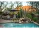 Backyard pool with rock waterfall feature and poolside dining area, set against a desert mountain backdrop at 10040 E Happy Valley Rd # 2022, Scottsdale, AZ 85255