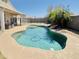 Backyard pool with safety fence, rock waterfall feature, mature palms and exterior patio at 1005 W 19Th Ave, Apache Junction, AZ 85120