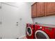 Well-equipped laundry room with a modern red washer and dryer set and upper cabinets at 1123 E Buckingham Ave, Gilbert, AZ 85297