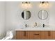 Bright bathroom with a double sink vanity, quartz countertop, wood cabinets and round mirrors above at 12620 N 70Th St, Scottsdale, AZ 85254