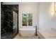 Elegant bathroom with a soaking tub, a sleek glass-enclosed shower, and a large window for natural light at 12620 N 70Th St, Scottsdale, AZ 85254
