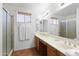 Well-lit bathroom with double sinks, framed mirrors, white towels and a glass-enclosed shower at 15516 W Verde Ln, Goodyear, AZ 85395