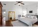 Bright bedroom featuring a plush bed, ceiling fan, and tall mirror, creating a cozy and inviting space at 15516 W Verde Ln, Goodyear, AZ 85395