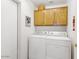Functional laundry area with washer, dryer, overhead cabinets, and neutral-toned walls at 15516 W Verde Ln, Goodyear, AZ 85395