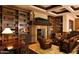 Elegant living room with a cozy fireplace, beautiful bookcases, and comfortable leather seating at 15516 W Verde Ln, Goodyear, AZ 85395