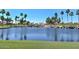 Scenic view of a pond with a waterfall feature, surrounded by palm trees and lush landscaping at 15516 W Verde Ln, Goodyear, AZ 85395