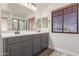 Bathroom with gray cabinets, framed mirrors, double sinks and a privacy window at 15604 N 173Rd Ln, Surprise, AZ 85388