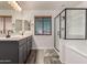 Bathroom featuring double sinks, framed mirrors, walk in shower, soaking tub, and gray cabinets at 15604 N 173Rd Ln, Surprise, AZ 85388