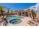 Scenic backyard with pool and spa, surrounded by rocks, palm trees, and covered patio at 15903 N 138Th Ave, Surprise, AZ 85374