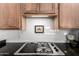 Modern gas cooktop with stainless steel and black finishes, complemented by white subway tile at 16670 N 109Th Way, Scottsdale, AZ 85255