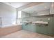 Bright bathroom featuring double sinks, a soaking tub, tile flooring, and a large window providing natural light at 1731 E Evans Dr, Phoenix, AZ 85022