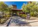 Community clubhouse featuring a covered entrance, lush landscaping, and shaded seating areas at 20698 W Meadowbrook Ave, Buckeye, AZ 85396